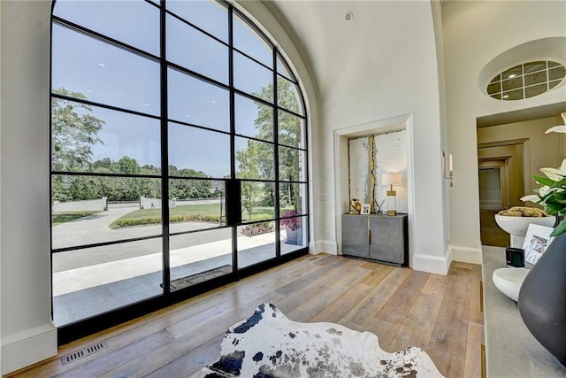 entryway with visible vents, baseboards, a high ceiling, and hardwood / wood-style floors
