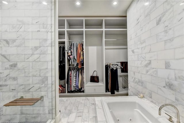 full bathroom with recessed lighting, a shower stall, a walk in closet, and a jetted tub