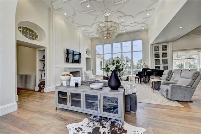 living room with built in features, a fireplace, a notable chandelier, and a towering ceiling