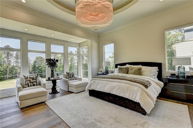 bedroom with recessed lighting, wood finished floors, and a tray ceiling