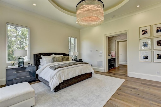 bedroom with a tray ceiling, multiple windows, and baseboards
