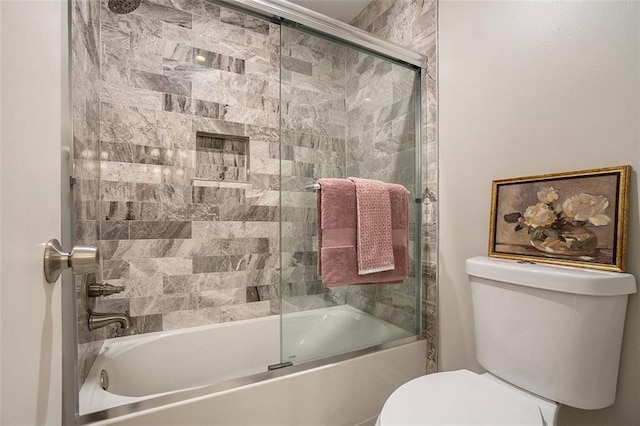 bathroom featuring toilet and combined bath / shower with glass door