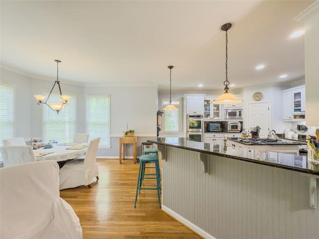 710 Bentgrass Ct, Dacula, GA 30019 - kitchen with appliances with stainless steel finishes, light wood-style flooring, crown molding, a kitchen breakfast bar, and white cabinetry