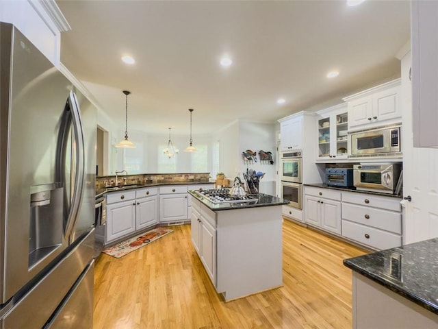 710 Bentgrass Ct, Dacula, GA 30019 - kitchen featuring appliances with stainless steel finishes, light wood finished floors, white cabinetry, hanging light fixtures, and a peninsula