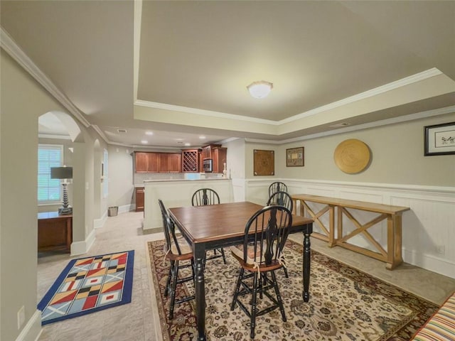 710 Bentgrass Ct, Dacula, GA 30019 - dining room featuring a raised ceiling, arched walkways, ornamental molding, and wainscoting