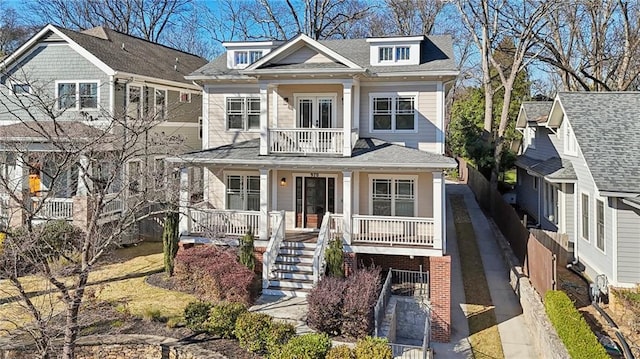 view of front of property with a porch, a balcony, stairway, and roof with shingles