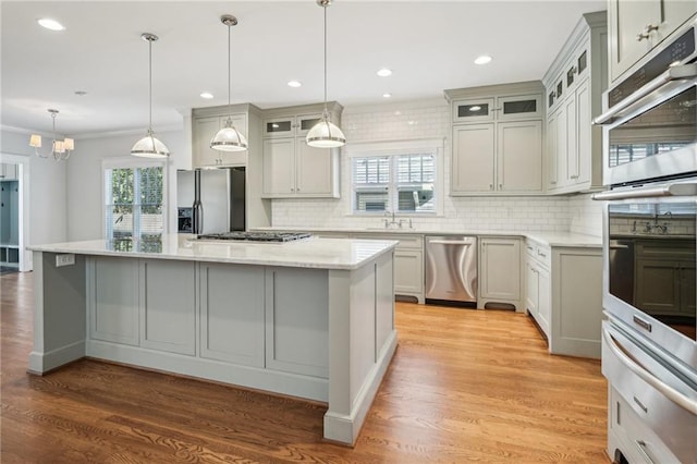 kitchen featuring a warming drawer, backsplash, a center island, stainless steel appliances, and light wood-style floors