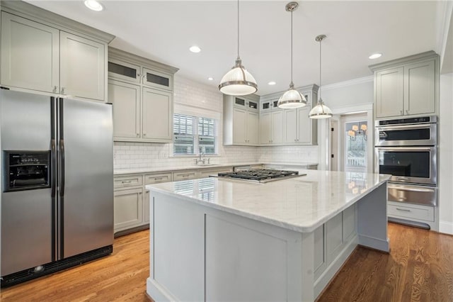 kitchen featuring light stone countertops, light wood-style flooring, appliances with stainless steel finishes, a warming drawer, and a center island