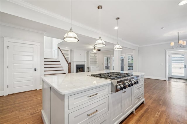 kitchen with ornamental molding, wood finished floors, baseboards, and stainless steel gas stovetop