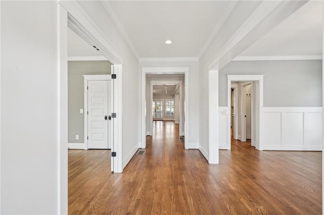 hall with visible vents, a wainscoted wall, wood finished floors, and crown molding