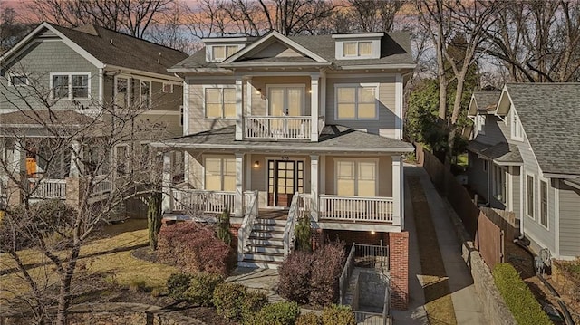 view of front of property featuring stairs, a porch, a balcony, and french doors