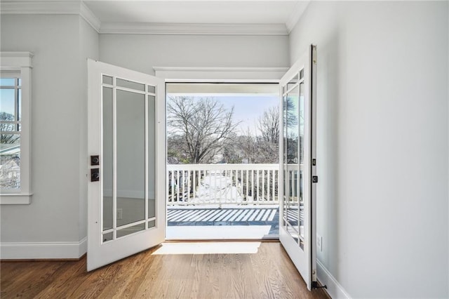 doorway to outside featuring baseboards, wood finished floors, and ornamental molding