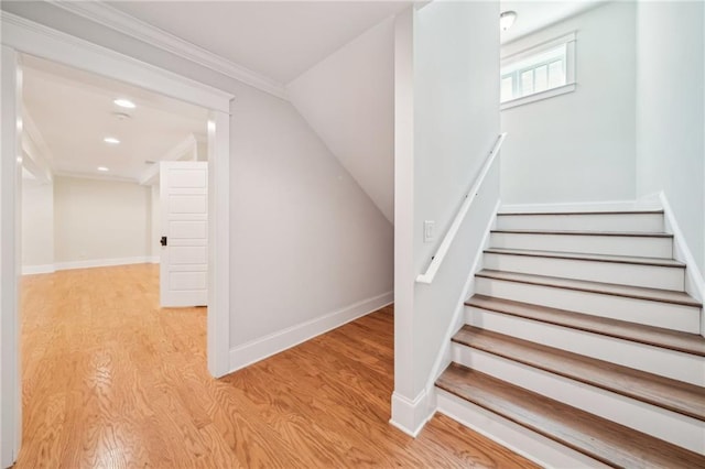 stairway with recessed lighting, wood finished floors, baseboards, and ornamental molding