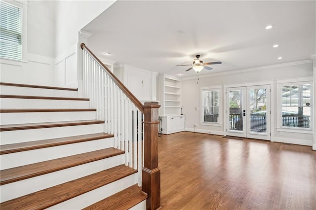 stairway with built in features, wood finished floors, recessed lighting, ceiling fan, and crown molding