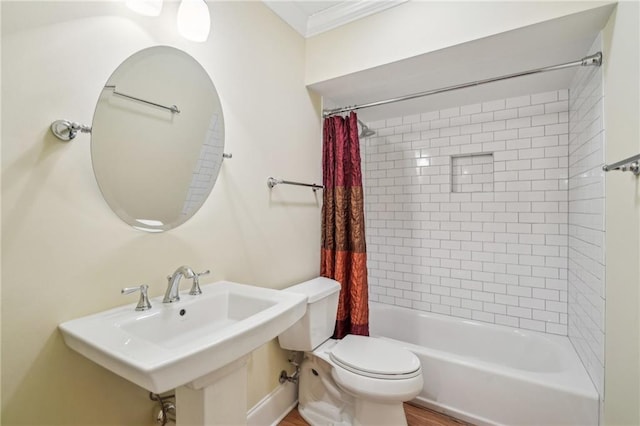 bathroom featuring ornamental molding, toilet, shower / bathtub combination with curtain, and a sink