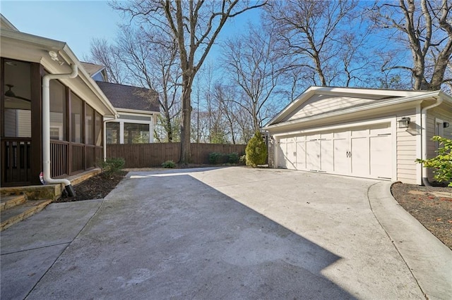 exterior space featuring fence, a garage, and a sunroom