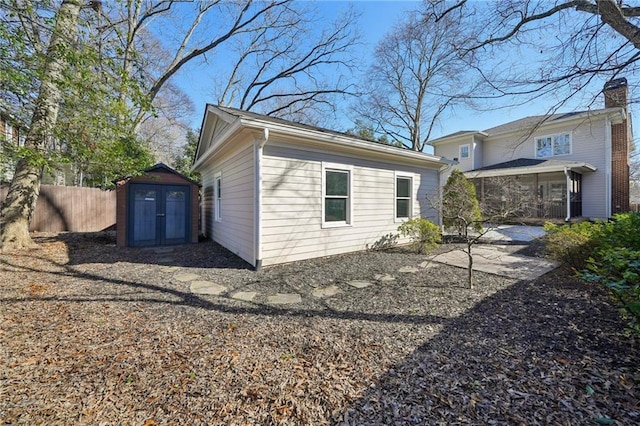 view of property exterior with a storage shed, an outdoor structure, and fence