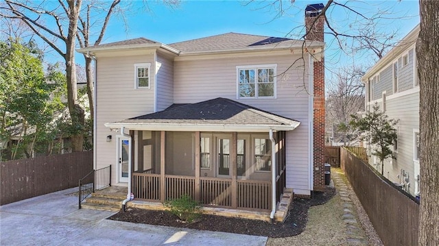 back of property with fence, a shingled roof, a chimney, and a sunroom