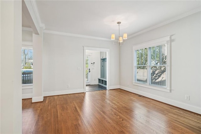 interior space with a healthy amount of sunlight, an inviting chandelier, wood finished floors, and ornamental molding