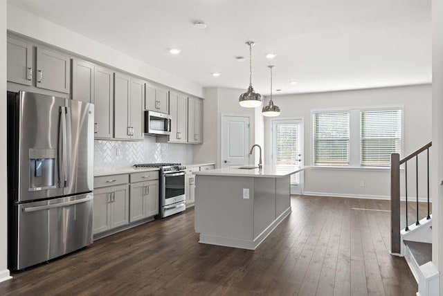 kitchen featuring gray cabinetry, stainless steel appliances, and a kitchen island with sink