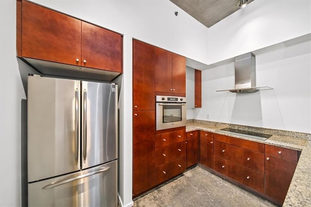 kitchen with light stone counters, wall chimney range hood, and stainless steel appliances