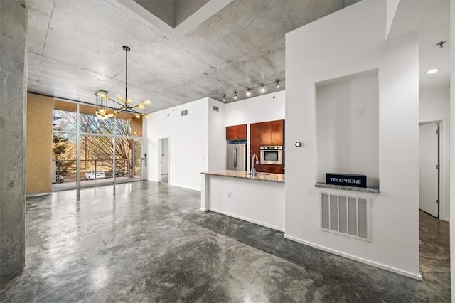 kitchen featuring pendant lighting, sink, stainless steel appliances, light stone countertops, and an inviting chandelier