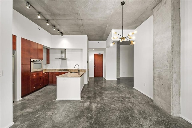 kitchen featuring sink, light stone counters, pendant lighting, oven, and wall chimney range hood