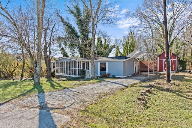 view of front of property with a sunroom, a front lawn, and a storage shed