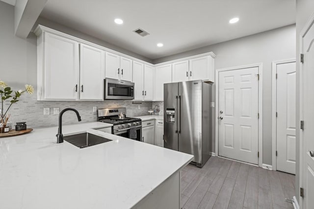 kitchen with stainless steel appliances, sink, white cabinets, and kitchen peninsula