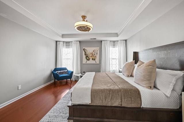 bedroom with multiple windows, a tray ceiling, crown molding, and hardwood / wood-style flooring