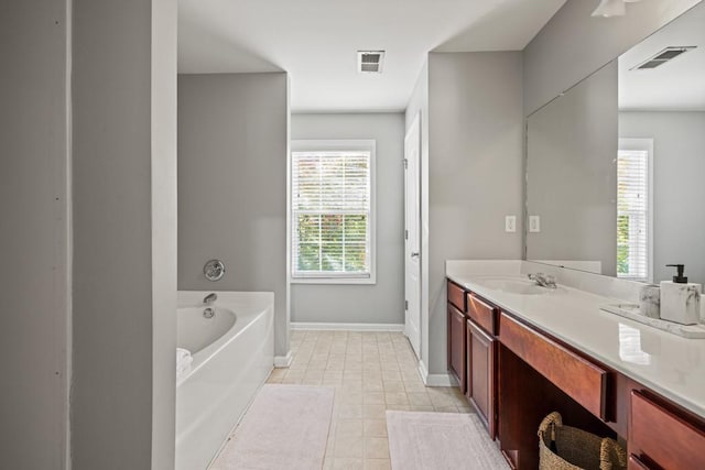 bathroom with vanity, a healthy amount of sunlight, a bath, and tile patterned floors