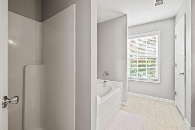 bathroom with tile patterned flooring and a tub