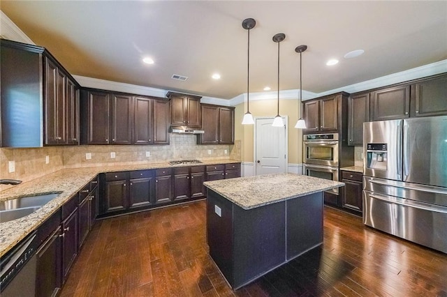 kitchen with tasteful backsplash, appliances with stainless steel finishes, dark wood-type flooring, and pendant lighting