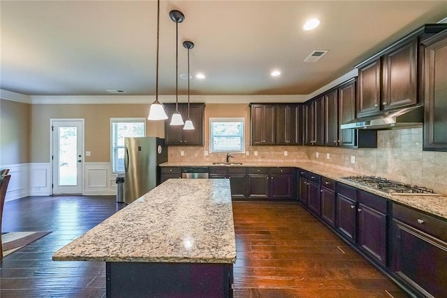 kitchen with under cabinet range hood, a wainscoted wall, stainless steel appliances, a sink, and dark brown cabinets