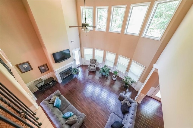 living area with a fireplace with flush hearth, a wealth of natural light, a high ceiling, and hardwood / wood-style floors