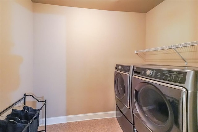 washroom with laundry area, tile patterned floors, washing machine and clothes dryer, and baseboards