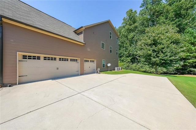 view of home's exterior featuring a garage, concrete driveway, and a lawn