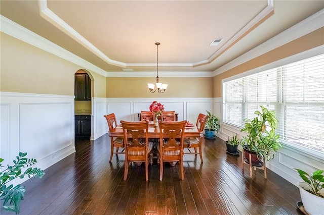 dining space featuring arched walkways, a tray ceiling, dark wood-type flooring, and visible vents