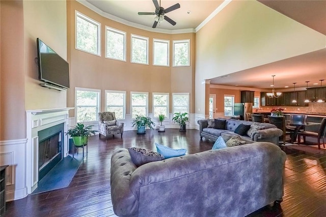 living area featuring ornamental molding, dark wood-style flooring, and wainscoting