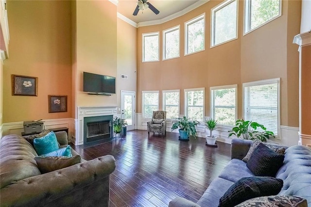 living room with a fireplace with flush hearth, plenty of natural light, dark wood-style flooring, and ornamental molding