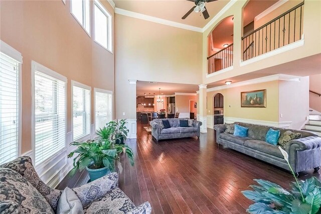 living room featuring ceiling fan, wood-type flooring, plenty of natural light, and crown molding