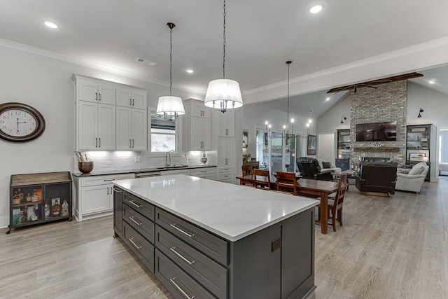 1889 Jefferson River Rd, Jefferson, GA 30549 - kitchen with gray cabinetry, a kitchen island, light wood-type flooring, decorative backsplash, and a large fireplace