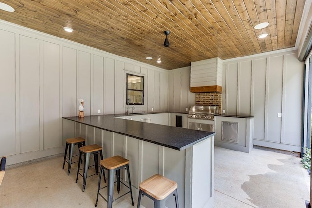 1889 Jefferson River Rd, Jefferson, GA 30549 - kitchen featuring a decorative wall, wooden ceiling, dark countertops, custom range hood, and white cabinetry