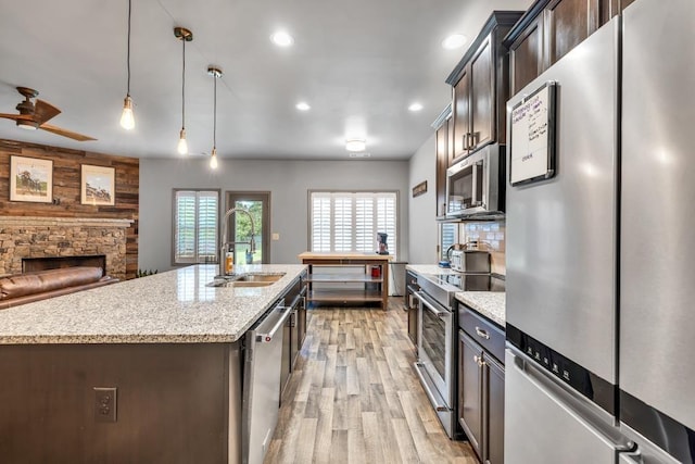 386 Summersong Pl, Talmo, GA 30575 - kitchen with appliances with stainless steel finishes, light wood-type flooring, light stone counters, open floor plan, and a stone fireplace