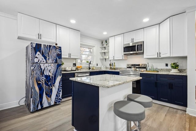 7994 Devonshire Dr, Jonesboro, GA 30238 - kitchen with appliances with stainless steel finishes, blue cabinets, open shelves, light wood-style floors, and recessed lighting