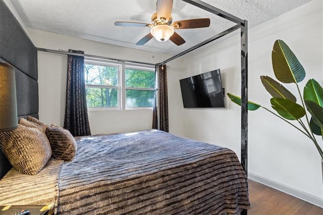 bedroom with a textured ceiling, ceiling fan, and dark hardwood / wood-style flooring