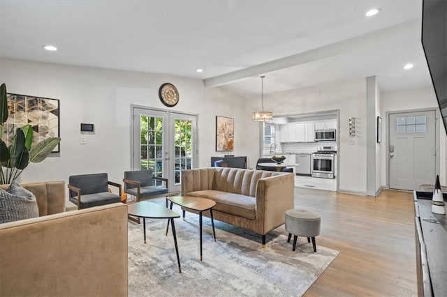 living room with light hardwood / wood-style floors, french doors, and a chandelier