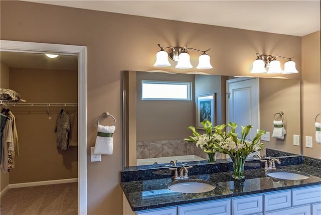 full bath featuring a spacious closet, a notable chandelier, baseboards, and a sink