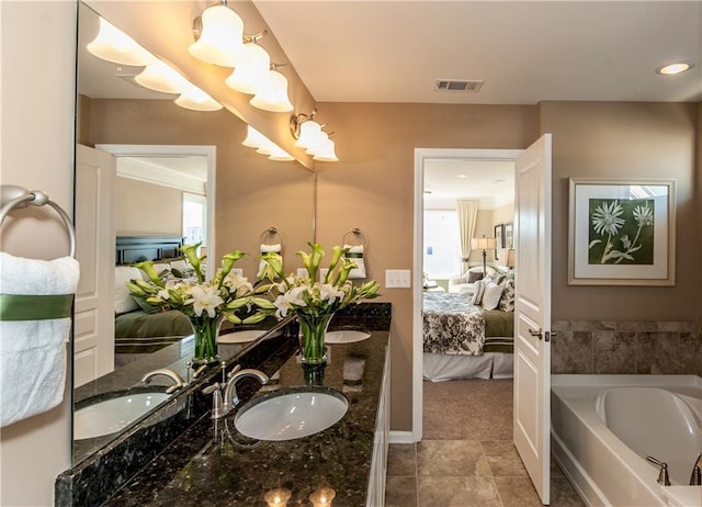 ensuite bathroom featuring a sink, visible vents, a garden tub, and ensuite bathroom