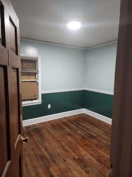 unfurnished room with crown molding, baseboards, and wood finished floors